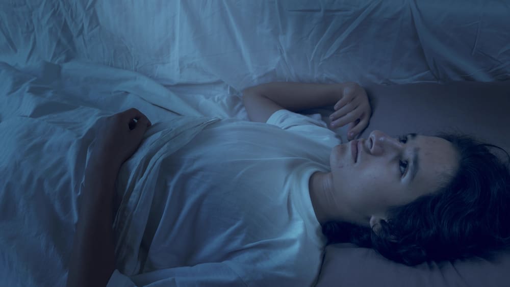 teenage boy suffering from insomnia lying in bed at night